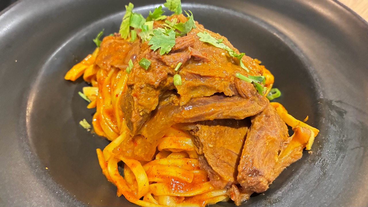 ข้าวซอยแห้งเสิร์ฟกับเนื้อและผักชีที่ร้านอ้ายแคบหมู เชียงราย