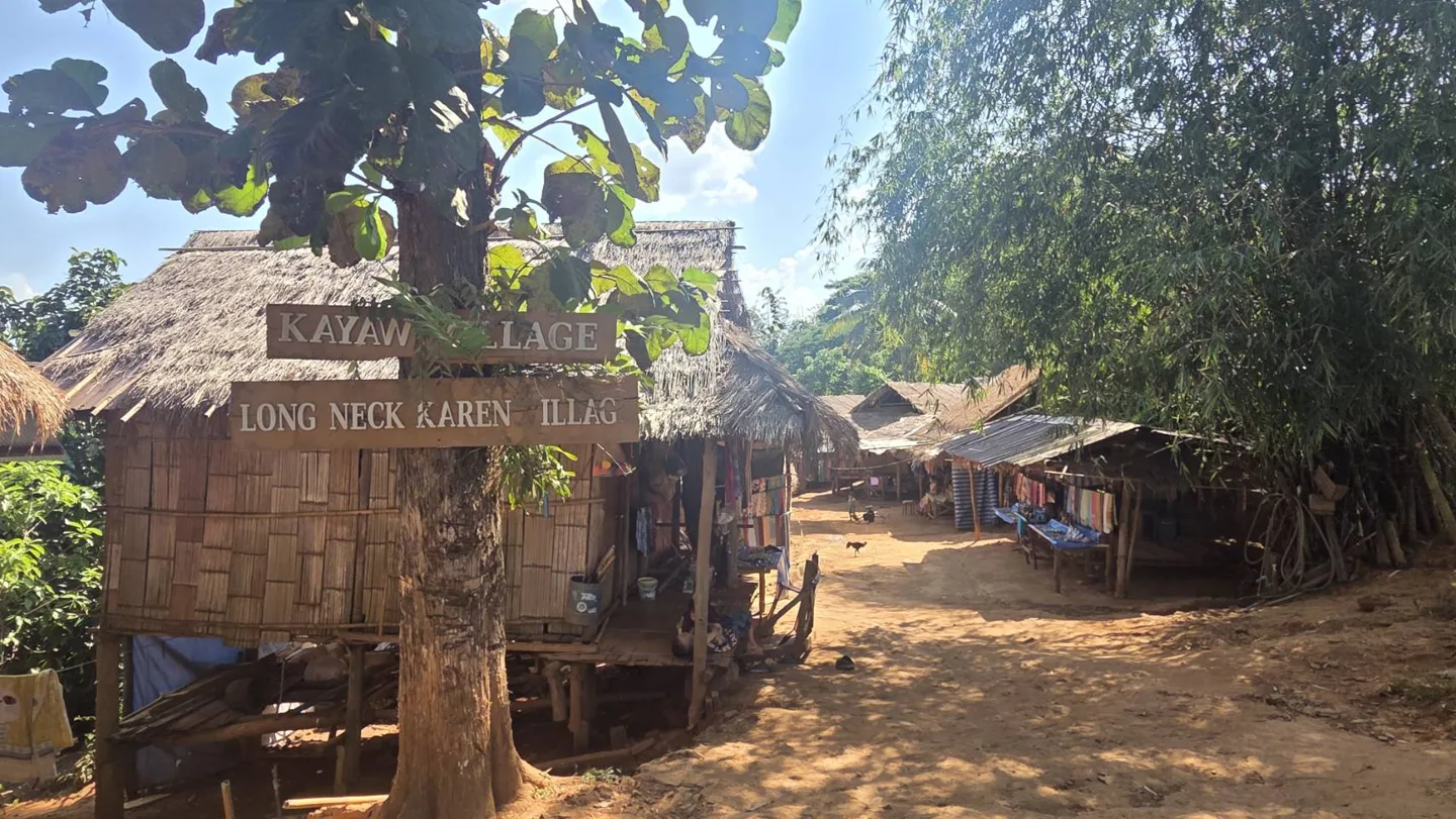 ทางเดินดินระหว่างเรือนไม้และหลังคามุงจากในบ้านป่าอ้อ